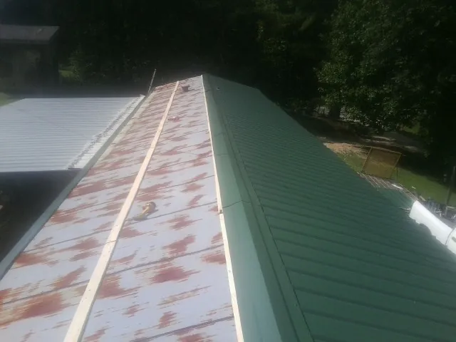 Old rusted panels beside newly installed green metal roofing — Wind Damage Roof Repair by Roofing Brothers in Mechanicsburg