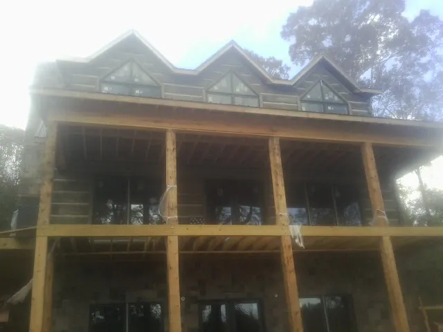 Dormers and porch framing on a large log home under construction — Roof Coating work by our crew in Mechanicsburg