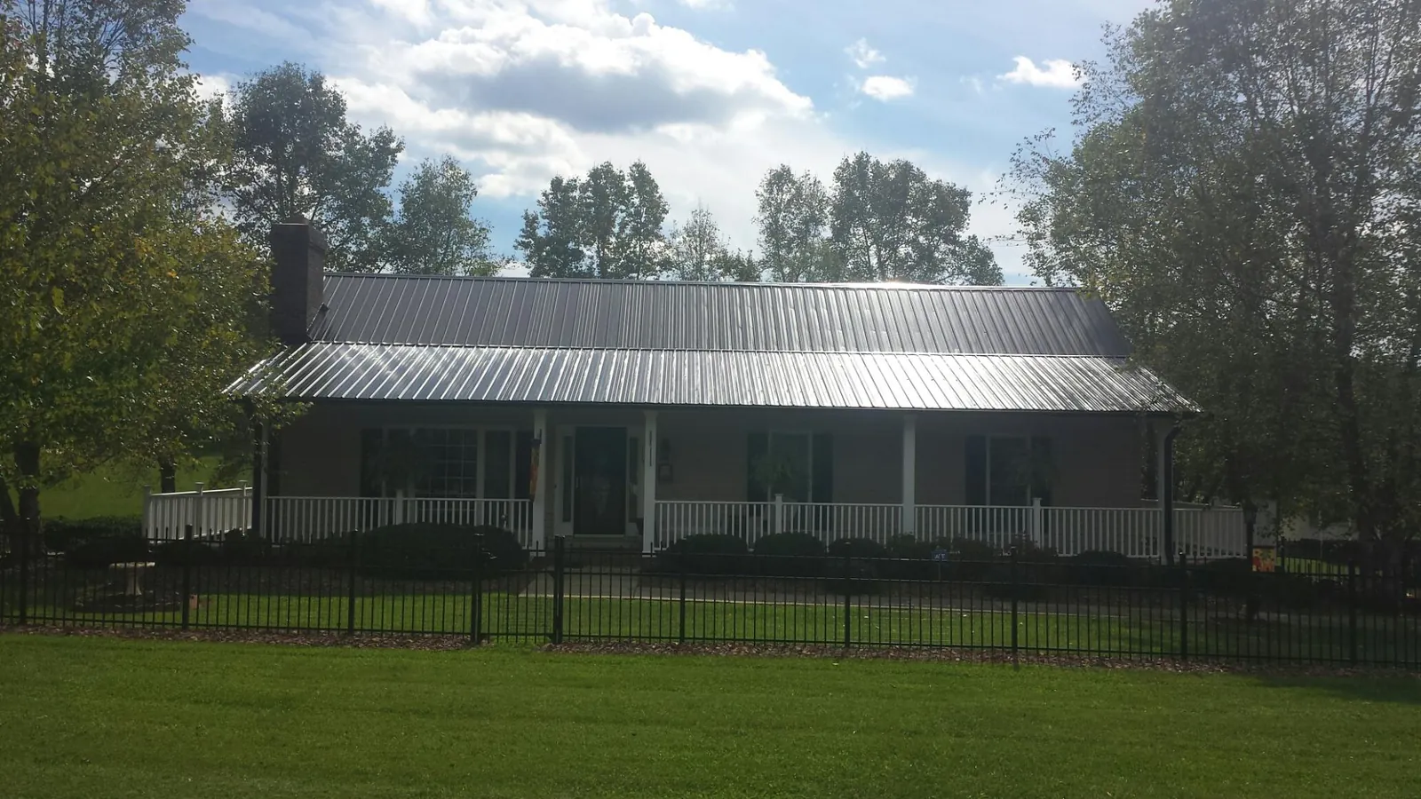 Gray metal roof on a brick ranch with a full width front porch — Gutter Guard Installation work by our crew in Mechanicsburg