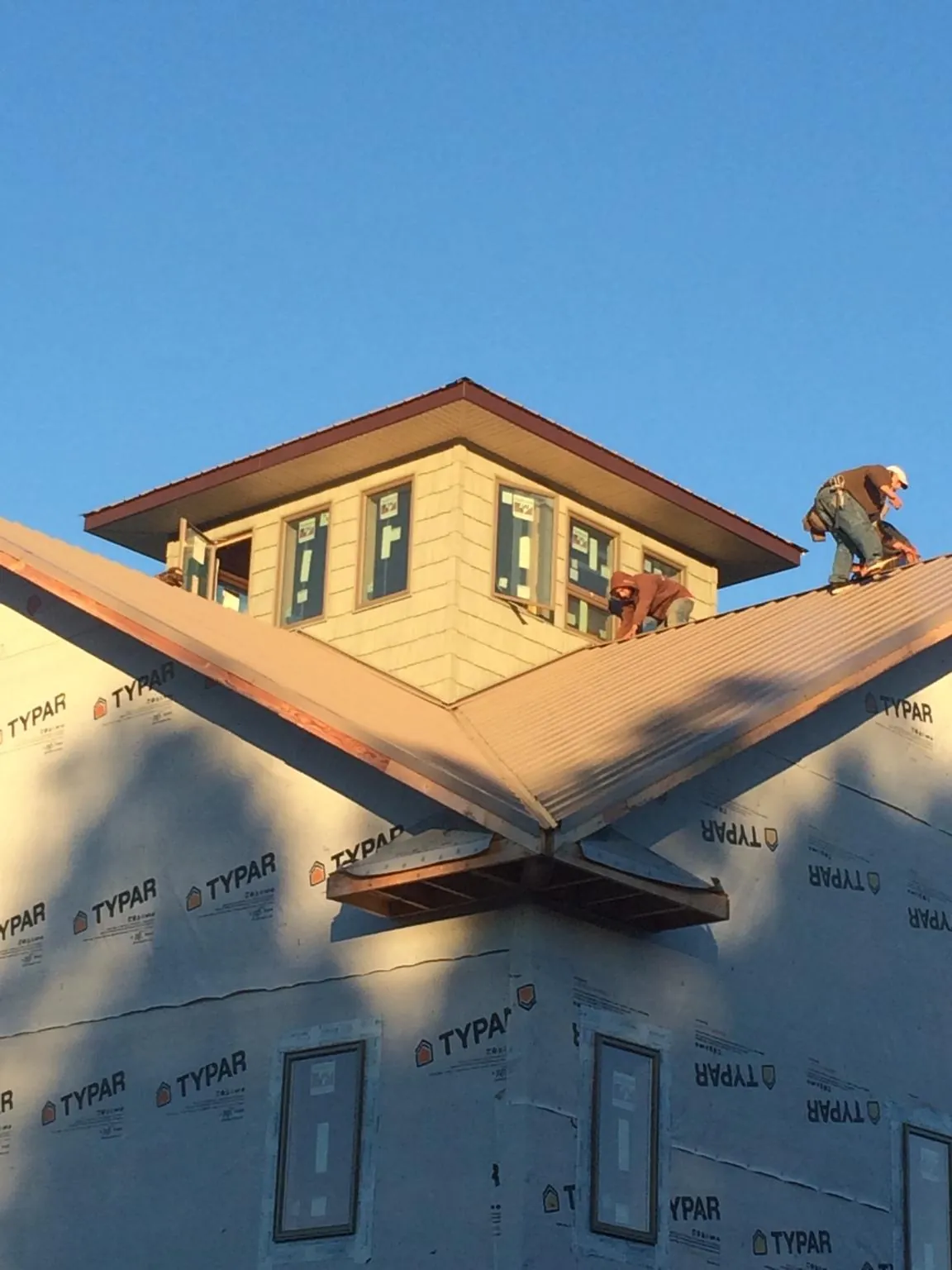 Roofers working around a rooftop cupola on a new metal roof at sunset — Roof Waterproofing in Mechanicsburg by Roofing Brothers